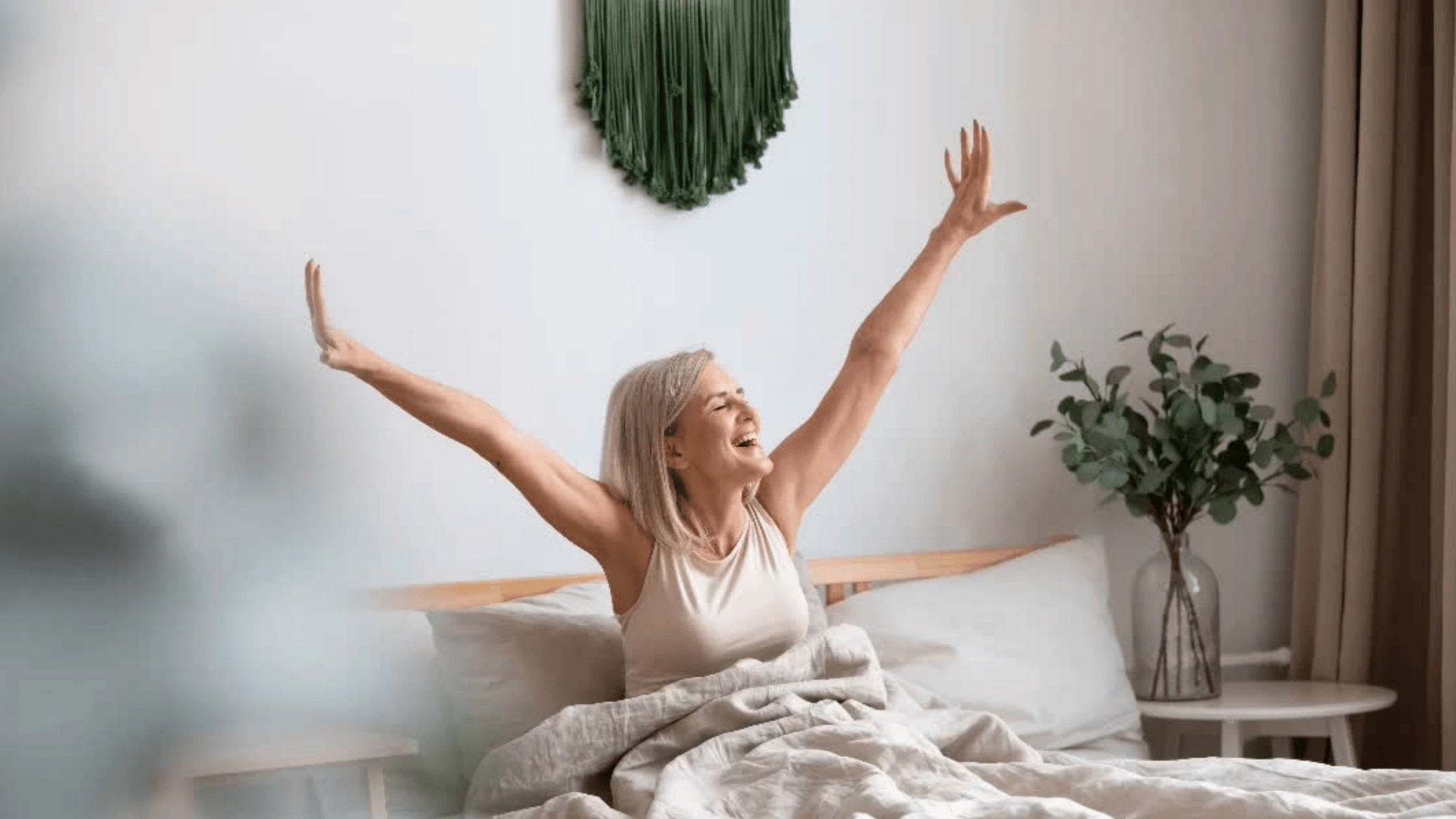 Chambre parentale calme et épurée avec une femme qui s’étire au réveil, ambiance sereine et propice au sommeil.